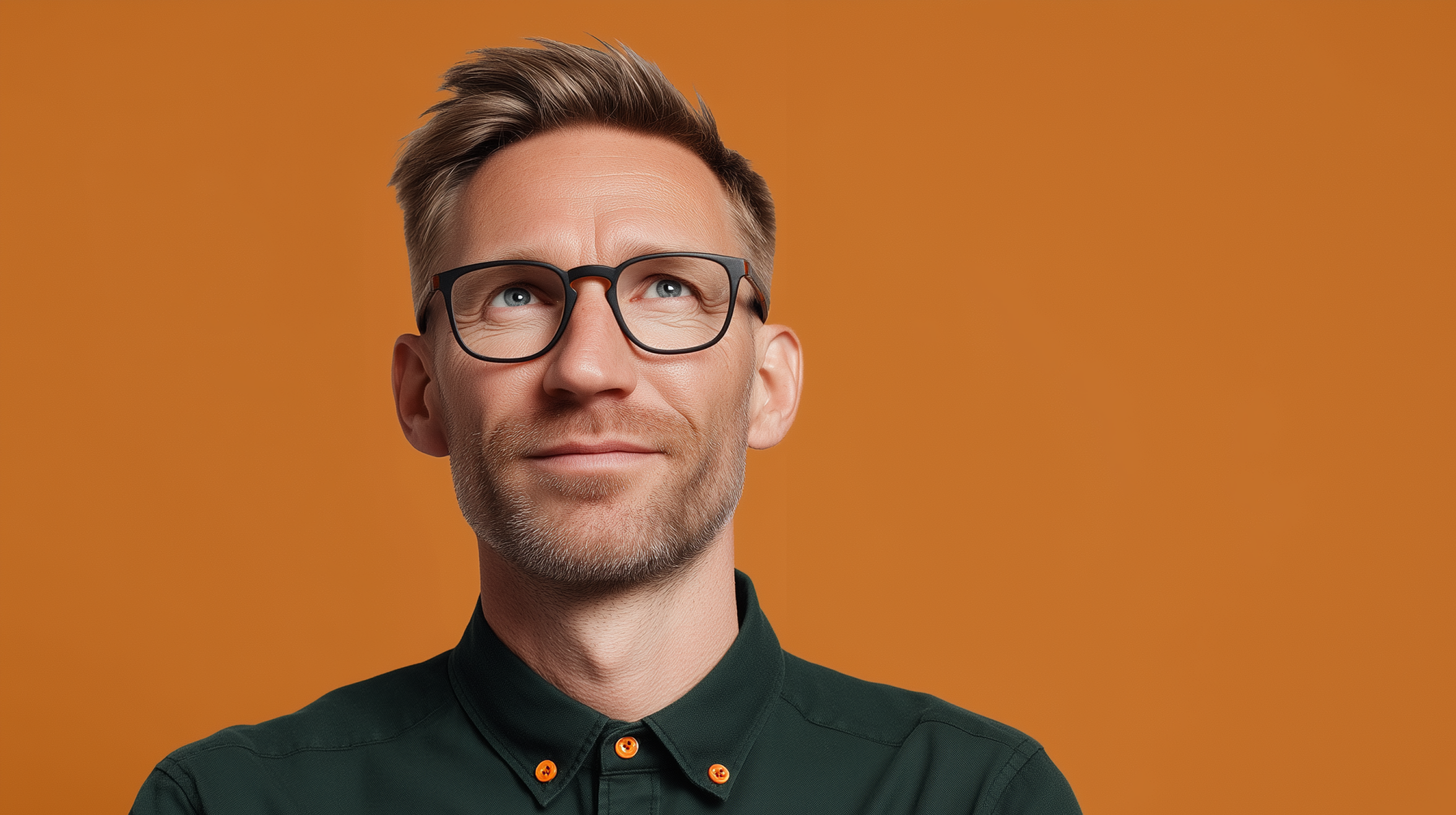 Arbeitgeber mit Brille in grünem Hemd vor orangefarbenem Hintergrund bei der Recherche nach bKV-Tarifen für sein Unternehmen.